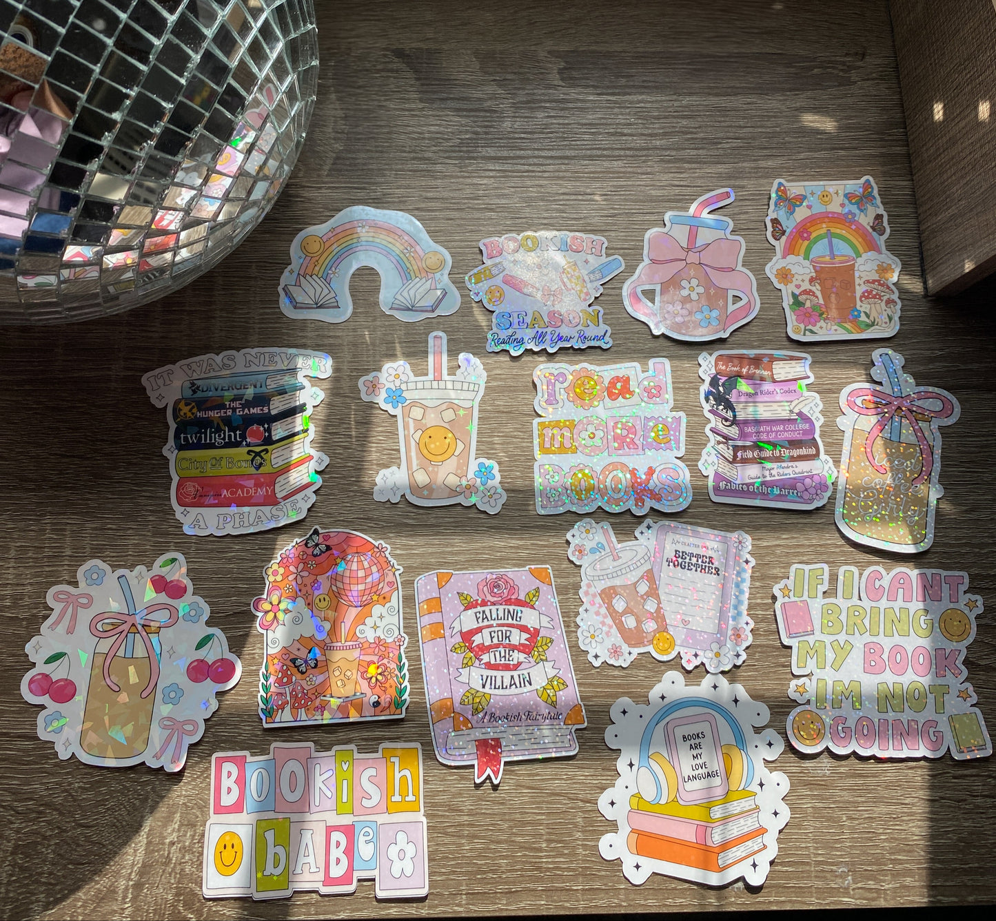 Collection of colorful stickers on a wooden surface with a disco ball in the background.