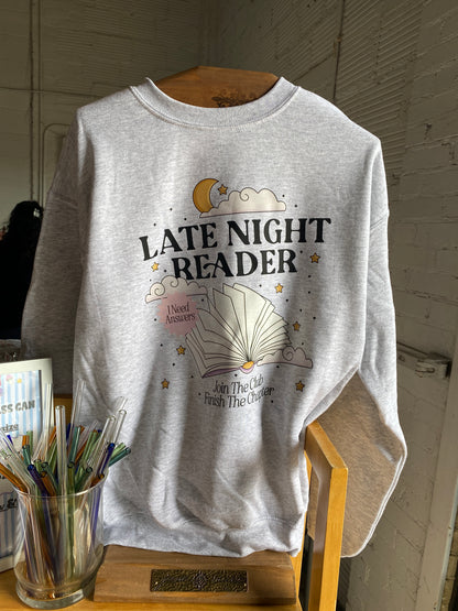 Gray tank top with 'Late Night Reader' text and graphics on a wooden surface.