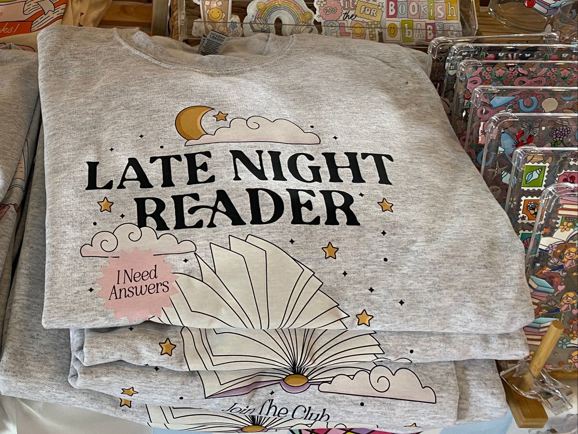 Ash gray Late Night Reader Sweatshirt on a table in a store setting.